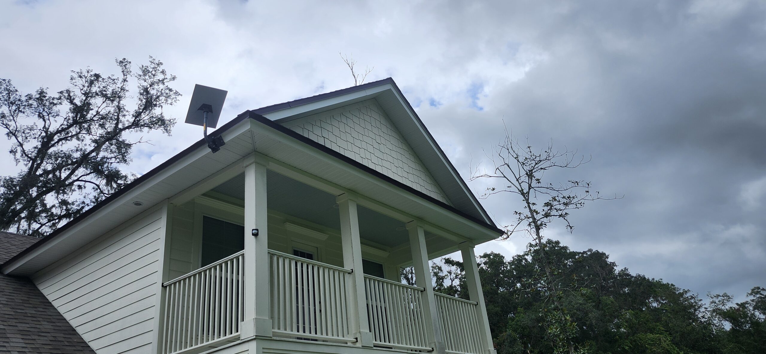 A Starlink Internet Antenna mounted to a roof. With a Outside cable run, down an outside wall, and a penetration through the wall that has a bushing and is siliconed.